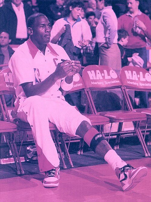 NBA player sitting on a foldable chair with left pant leg rolled up to knee