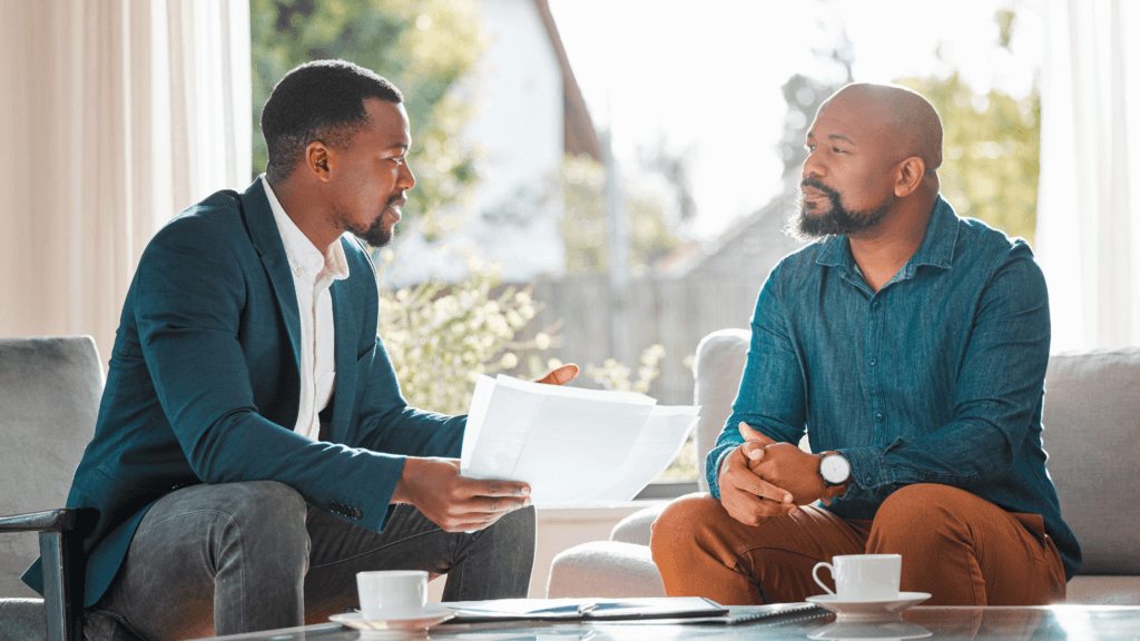 Two gentlemen conversing together sitting with 2 tea cups on coffee table
