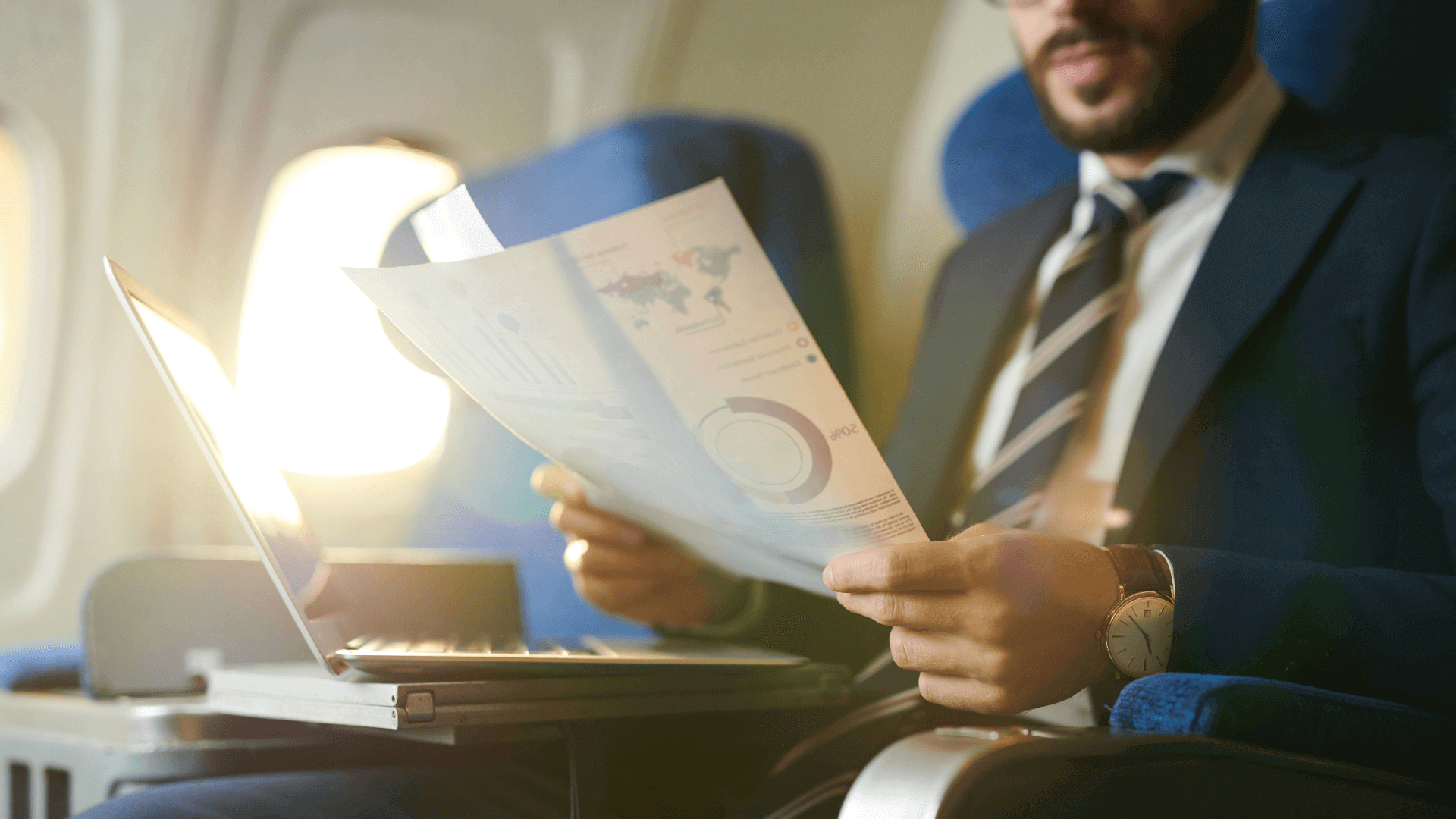 Businessman on a plane reading charts and figures